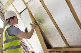 Accredited installer fitting loft insulation between rafters